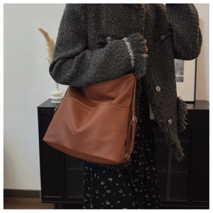 Detail of brown leather tote bag with large front pocket on wool coat outfit