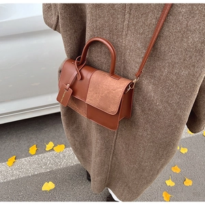 Detail of color-blocked brown handbag featuring smooth faux leather and matte suede texture