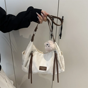 Dettaglio della borsa tote crema con spalline marroni e ciondolo a forma di cane in peluche