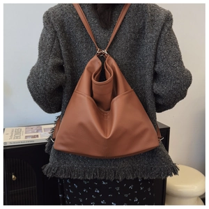 Brown leather backpack with grain texture shown on model in a modern home setting