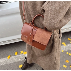 Detail of caramel brown contrast bag with suede texture and adjustable strap on a brown coat