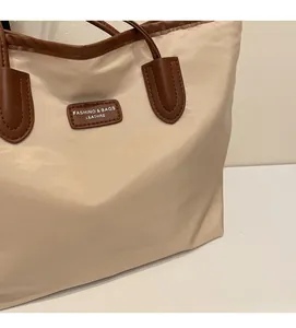 Detail of beige tote bag showing high-quality nylon texture and brown leather handle