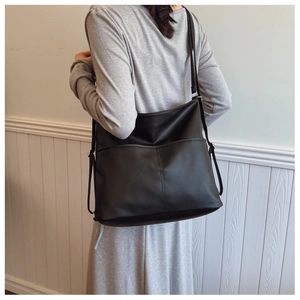 Model wearing a large black pebble grain tote bag with dual shoulder straps for commute