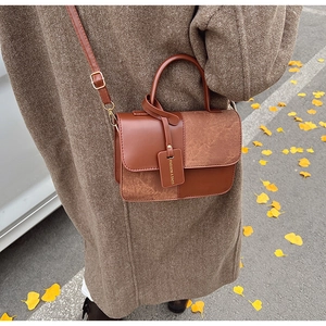Close-up of caramel patchwork handbag with mixed suede texture and fashion tag