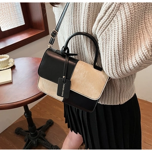 Detail view of stylish color-block crossbody bag with buckle flap and leather handle