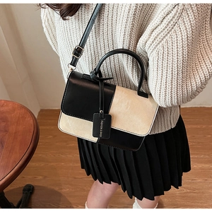 Detail of contrast color crossbody bag with leather tag and elegant top handle