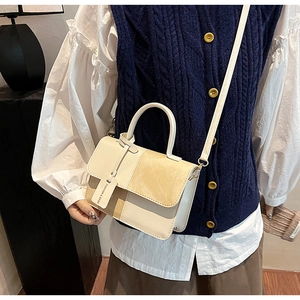 Detail view of retro color-block square bag on model showing crossbody and top handle use