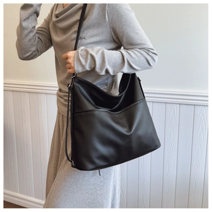 Detail of black large capacity tote bag with litchi texture and side pocket for commute