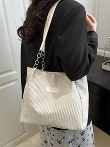 Cream white corduroy tote bag with silver chain strap shown in an indoor fashion shot
