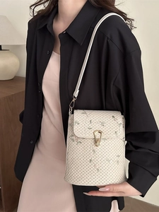 Sac seau tissé avec broderie florale et fermoir doré sur textile ivoire