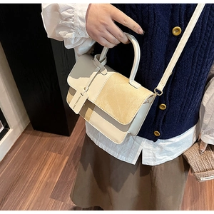 Detail showing contrast stitching and textured beige and khaki leather on the crossbody bag