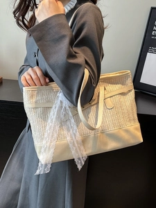 Large straw tote bag with leather trim and white lace bow detail shown on shoulder