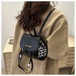 Detail view of mini black PU leather backpack with leopard print side panels and gold lettering