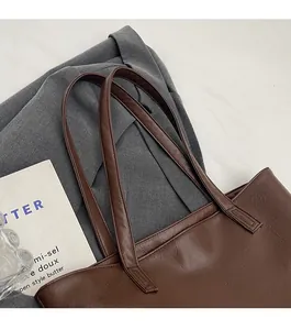Detail of sturdy shoulder straps and textured dark brown PU leather on large tote bag