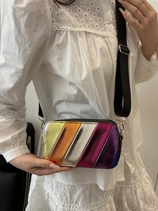 Sac bandoulière aux rayures métalliques colorées avec large sangle porté par un mannequin