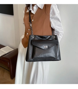 Detail of black soft leather tote bag featuring silver chain strap and metal buckle lock