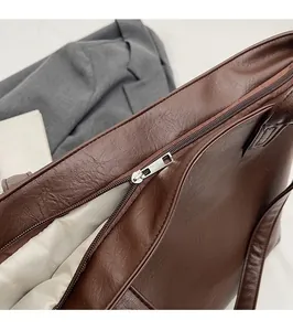 Close-up of smooth metal zipper and premium stitching on a brown leather tote bag