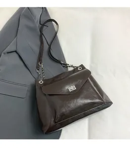 Close-up of the metal twist lock closure and chain strap on dark brown tote bag