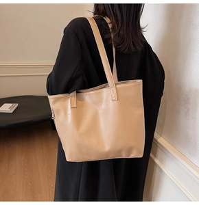 Macro view showing the soft pleated texture and side zipper of this large beige tote bag