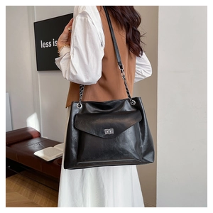 Detail of black leather tote bag with metal twist lock pocket and chain strap
