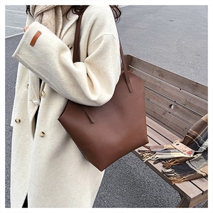 Deep brown lychee texture tote bag on a model wearing a winter coat on a city street