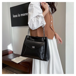 Detail of black faux leather tote with metal chain strap and silver twist-lock closure