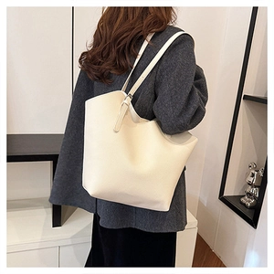 Close-up of off-white tote bag showing pebbled leather texture and metal buckle detail