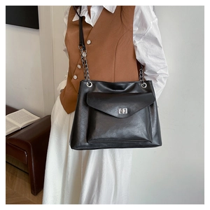 Detail of black leather tote bag with silver chain strap and metal buckle on the shoulder