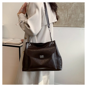 Detail of vintage brown tote bag featuring silver twist-lock and chain strap