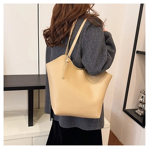 Detail of adjustable strap and pebble grain leather on a beige tote shoulder bag