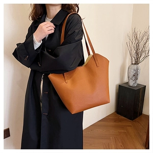 Detail of caramel faux leather tote bag showing fine lychee grain texture and winged design