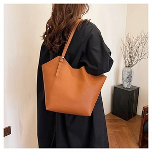 Caramel leather tote bag on shoulder showing large capacity and soft pebble texture