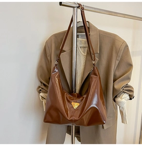 Detail of vintage brown glossy hobo tote with gold triangle logo on office blazer