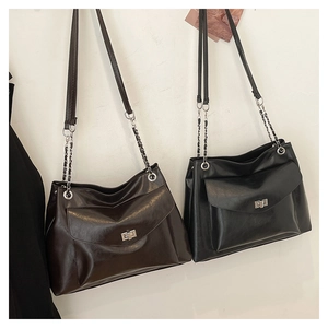 Close-up of large chain tote bags in dark brown and black faux leather with metal buckles