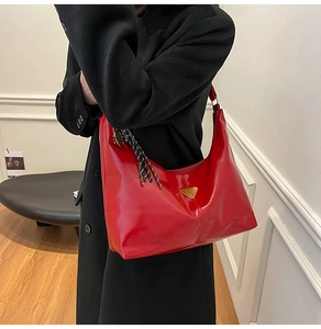 Detail of red glossy leather Hobo bag with golden logo and woven fringe tassel