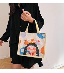 Detail of canvas tote bag featuring cute cartoon illustration and yellow handles