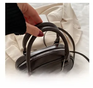 Detail einer dunkelbraunen Boston-Tasche mit glatter Lederstruktur und Silber-Reißverschluss