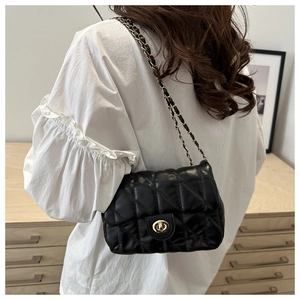 Close-up of black quilted shoulder bag with gold chain strap and metal swivel clasp