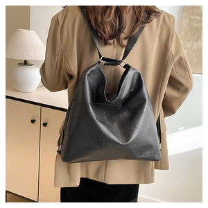 Detail of minimalist black pebbled leather tote bag with wide strap and silver ring