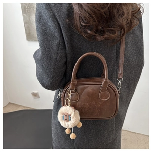 Detail der dunkelbraunen Tasche mit Lucky OHIO Prägung und Plüschlamm-Anhänger