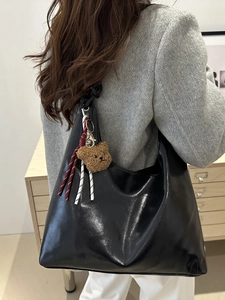 Trendige schwarze glänzende Tragetasche für Damen mit Bärenanhänger und Knotendetails