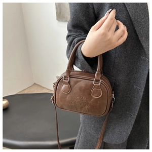 Close-up of brown textured leather bag with embossed Lucky Ohio Emu lettering and silver hardware