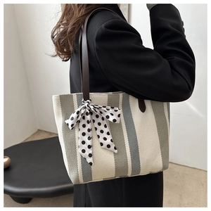 Detail der gestreiften Canvas-Tasche mit Polka-Dot-Schal und braunem Lederriemen am Model