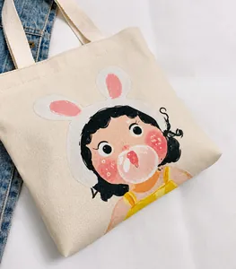 Detail of canvas bucket bag showing cute cartoon girl print and woven rope handles