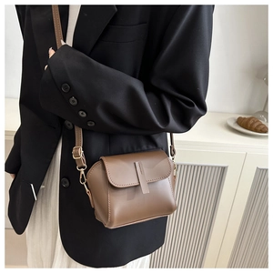 Detailansicht der braunen Wildleder-Muscheltasche mit goldenen Details am Schultergurt