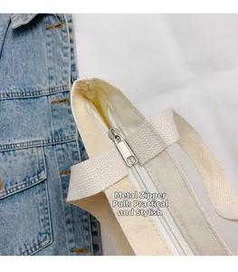 Dettaglio della cerniera in metallo e del manico in tela su una borsa beige secchiello