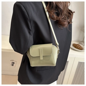 Rear view of a model wearing a light olive green crossbody bag with a sleek flap design