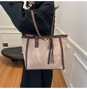 Detail einer großen beige Tote Bag mit braunem Lederriemen an einem Model