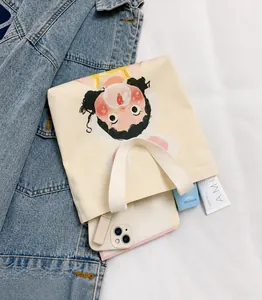 Detail of cute girl illustration on cream canvas tote bag with daily essentials inside