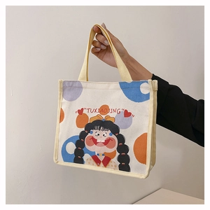 Detail of canvas tote bag with cute cartoon girl print and yellow woven handles